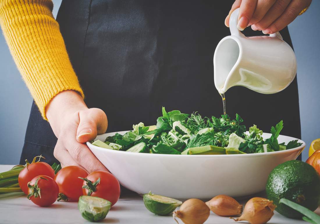 Pouring olive oil on salad