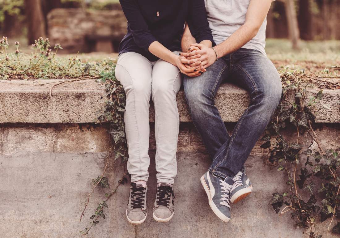 Couple sitting on wall holding hands