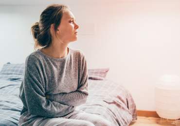 Woman sitting on her bed, arms folded