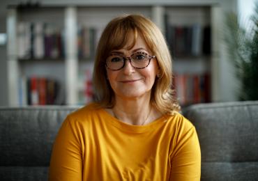 Middle aged woman with glasses smiling at the camera